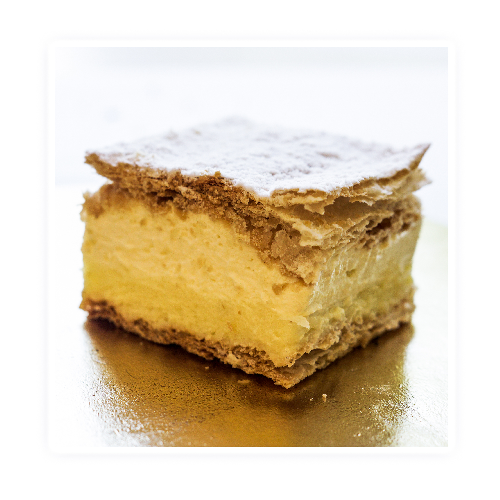 kremówka – ciasto francuskie przełożone kremem budyniowym i śmietaną ,wykończone cukrem pudrem.